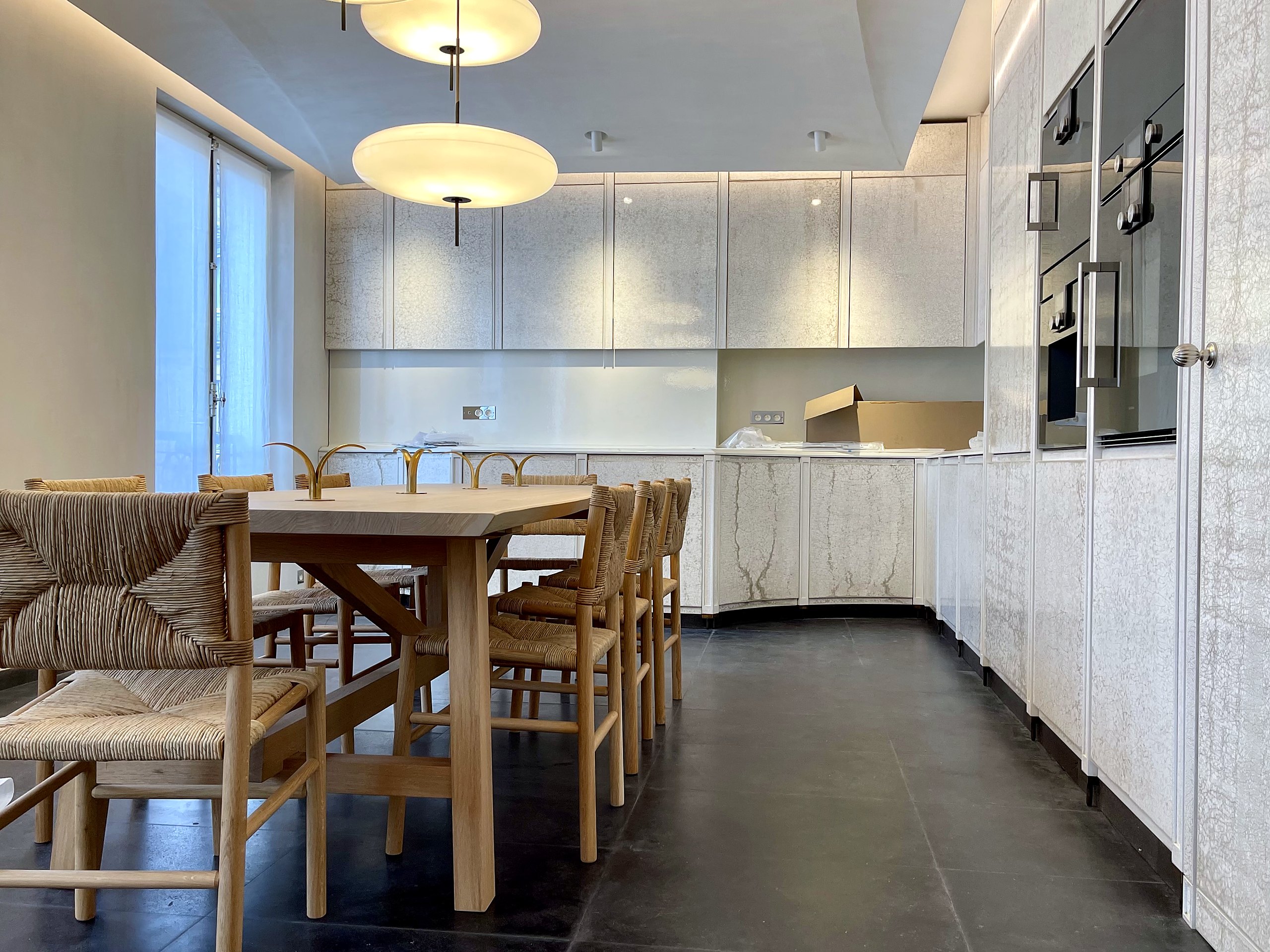 Cuisine : façades en laque craquelée blanche, plans de travail en pierre de lave émaillée, vue depuis la table