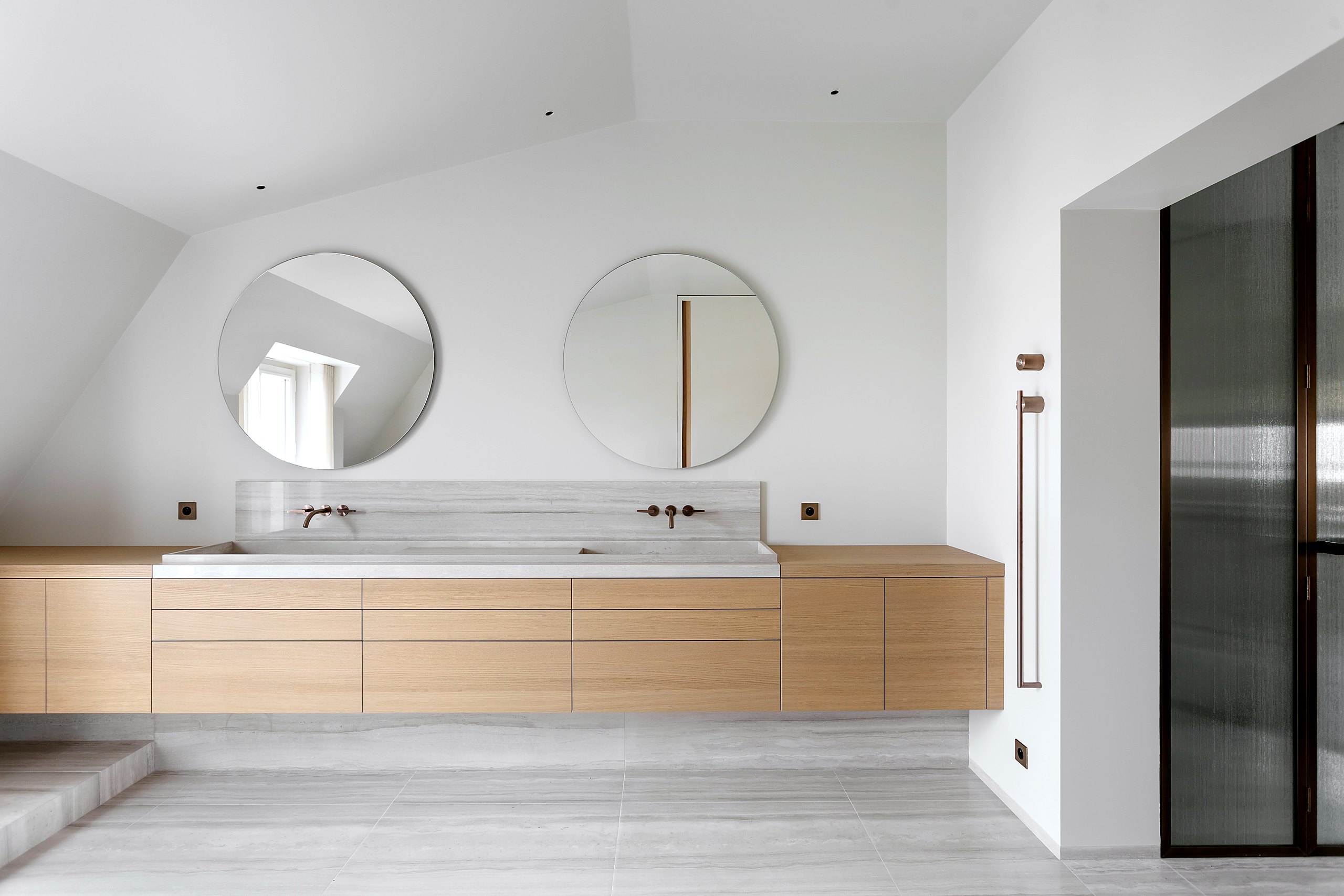 Salle de bain sur mesure — meuble en chêne clair, double vasque en pierre, miroirs ronds, serrurerie fine en laiton bronze médaille