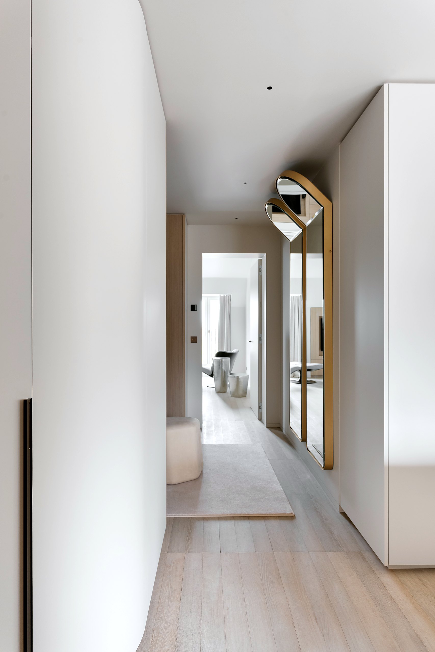 Dressing laqué à portes courbes, sol en chêne clair, miroir cintré encadré laiton