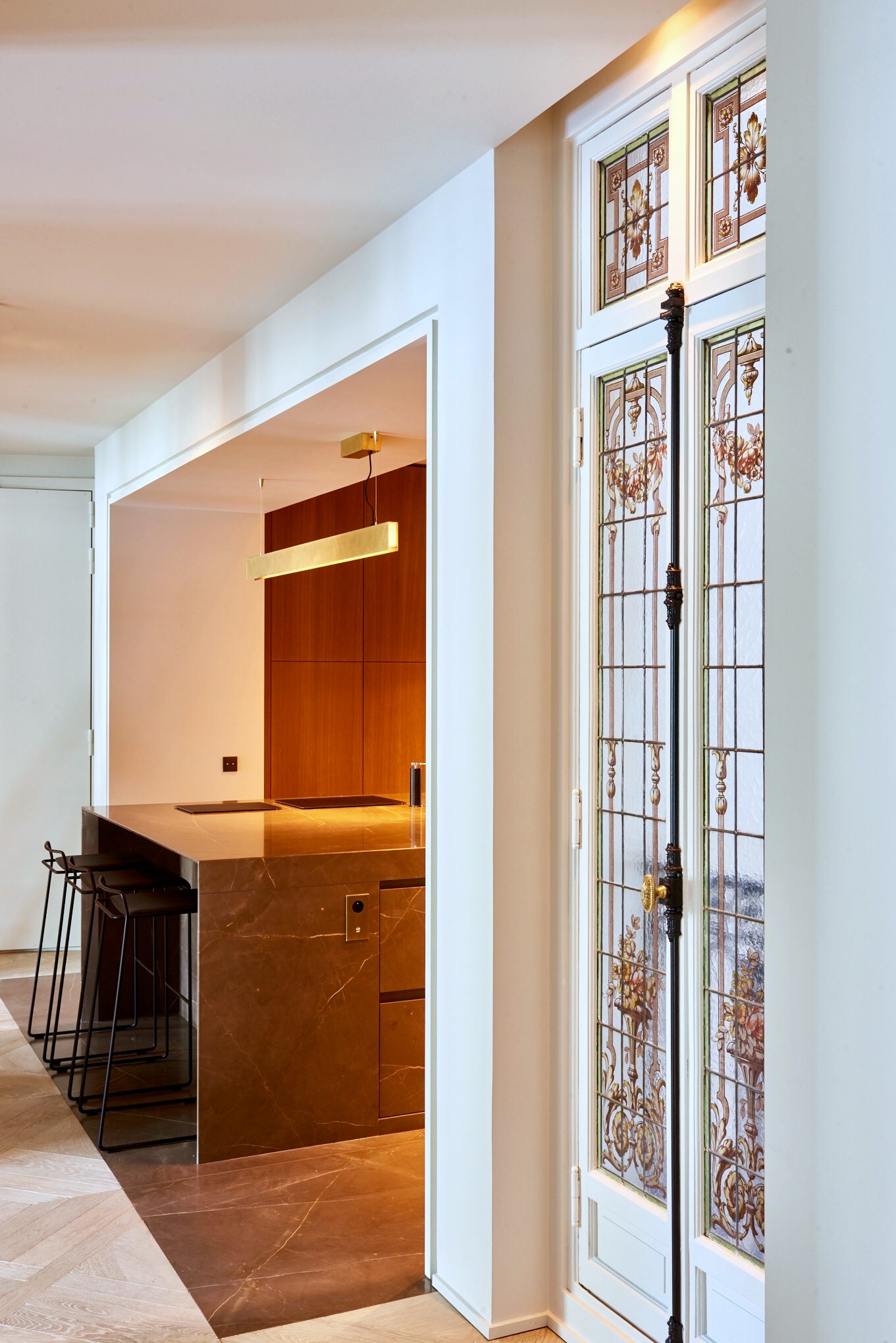 Vue sur la cuisine depuis le couloir, vitraux et îlot en marbre