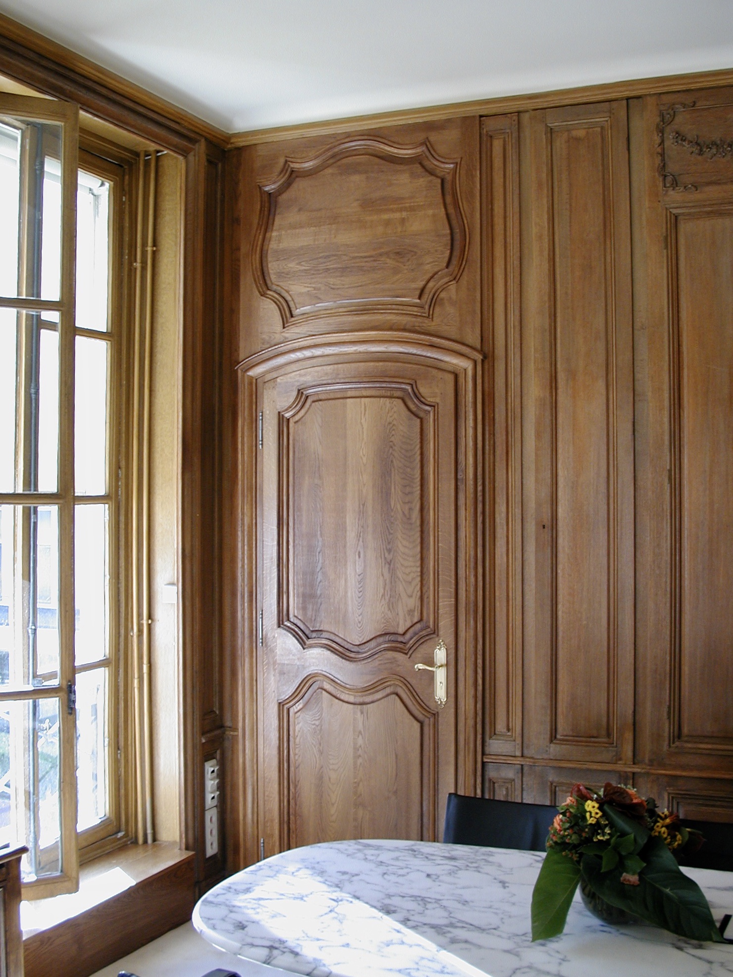Boiserie en chêne massif, patine cirée, porte à panneaux moulurés et fronton chantourné